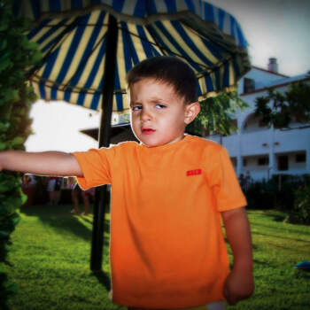 Niño enfadado triste jardín cesped verano sombrilla